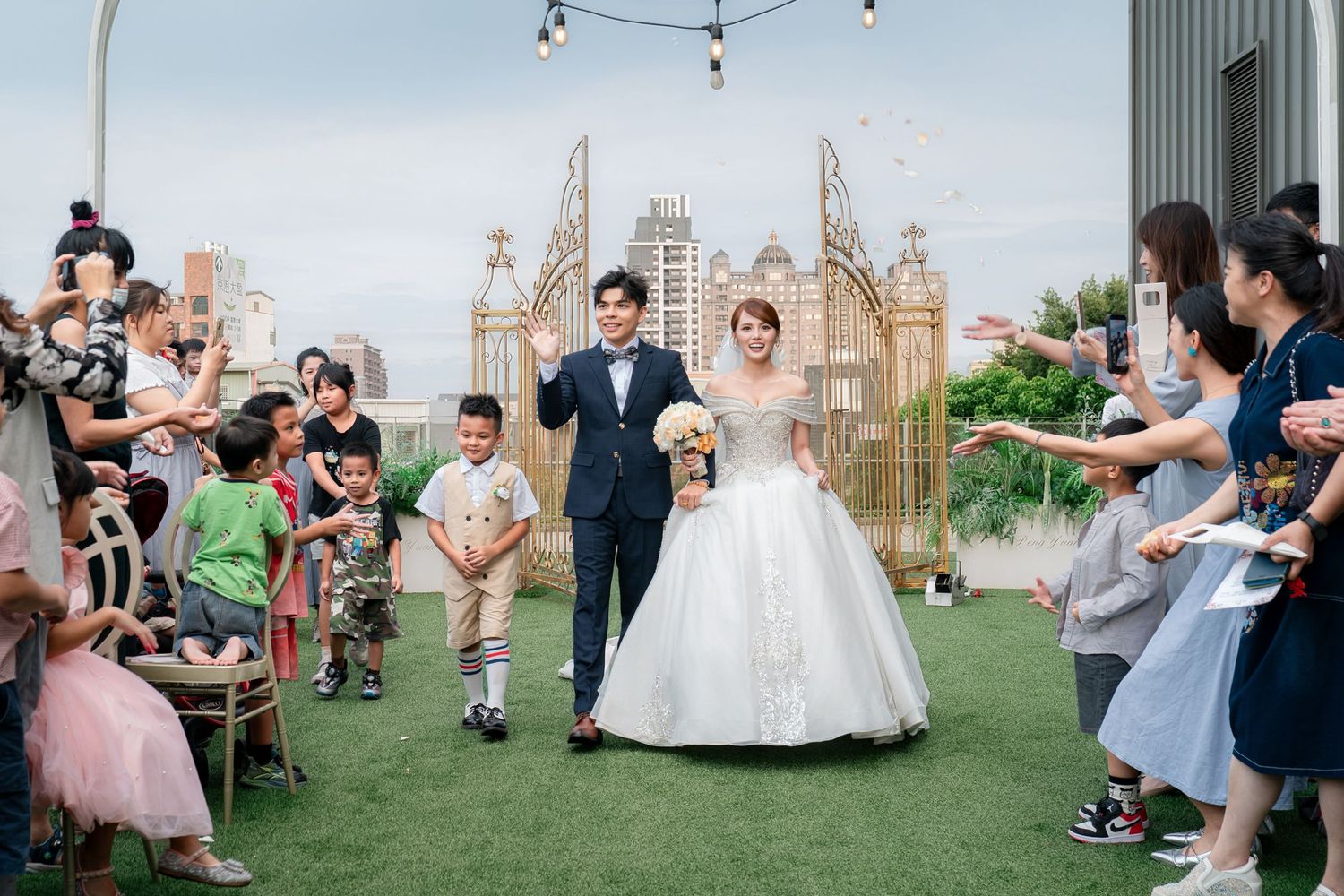 A joyful couple walks down the aisle at an outdoor wedding ceremony as guests celebrate with confetti.