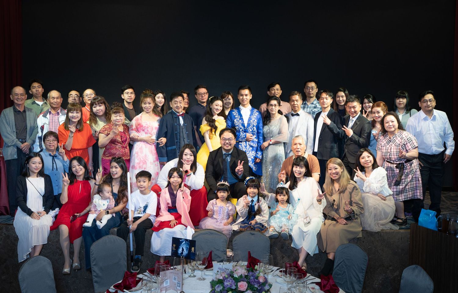 Large group of diverse people posing together for a formal group photo at an indoor celebration event.