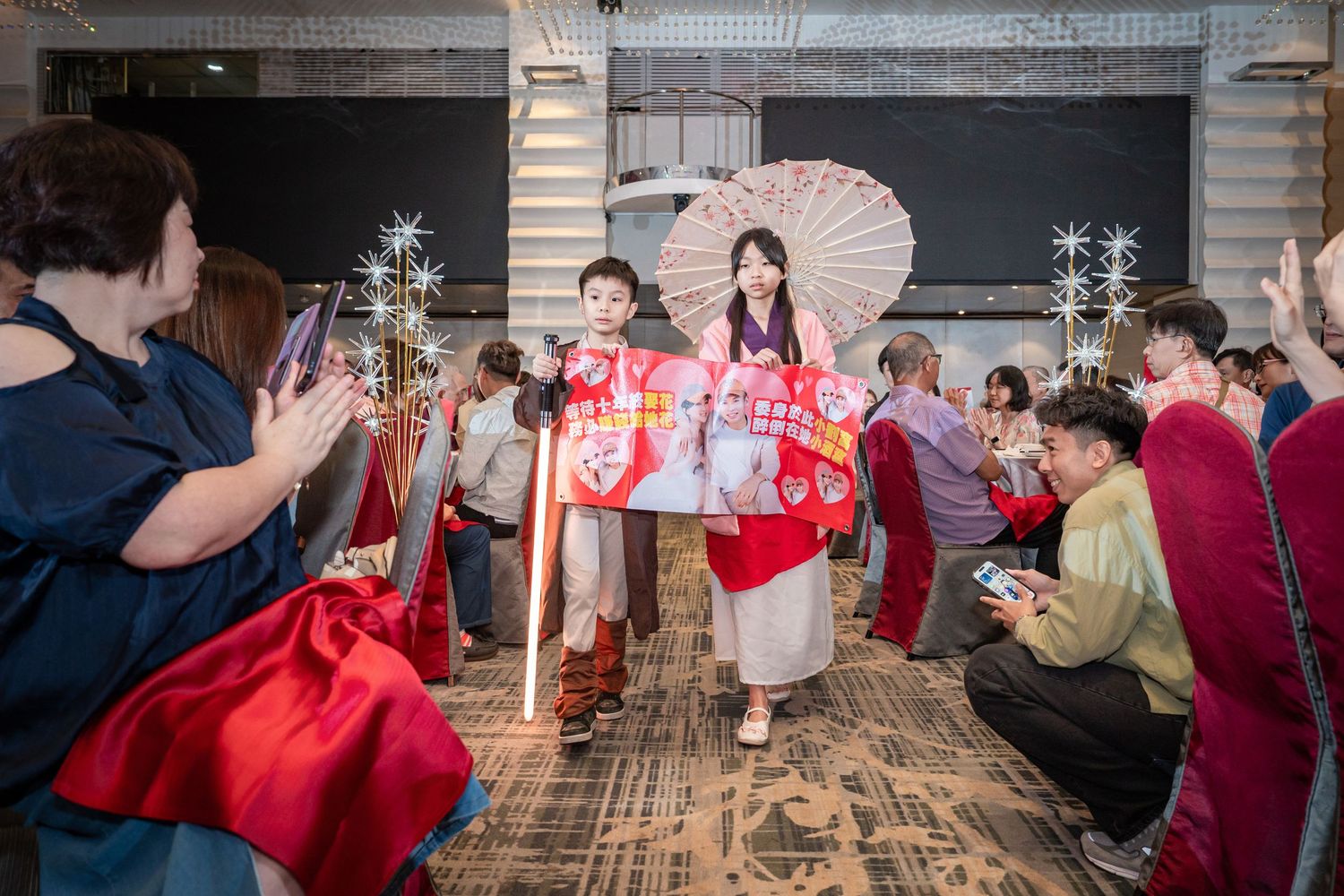 Couple in traditional Japanese attire walking through applauding guests at a wedding reception.