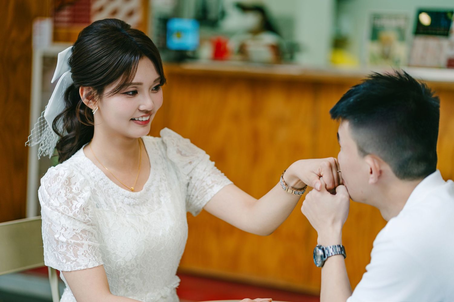 A romantic moment during a wedding ceremony as the groom kisses the bride's hand while seated at a table.