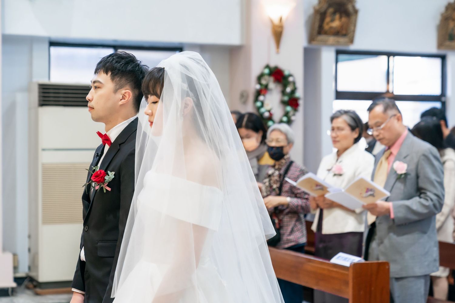 A couple during their wedding ceremony in a church with guests in attendance.
