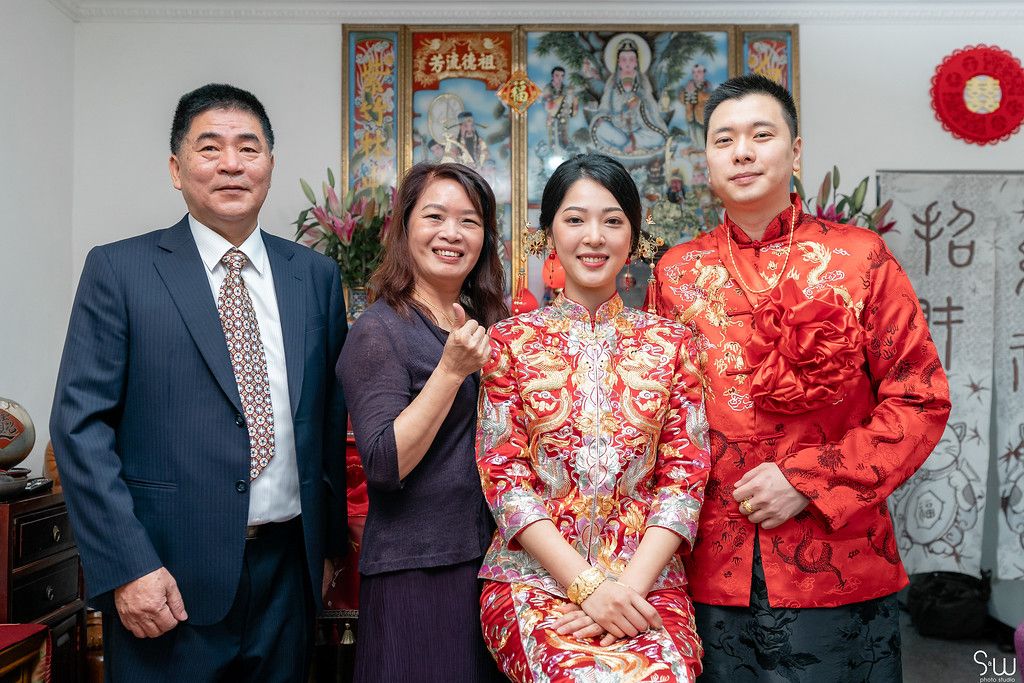 Traditional Chinese wedding scene with decorative wall art and red attire.