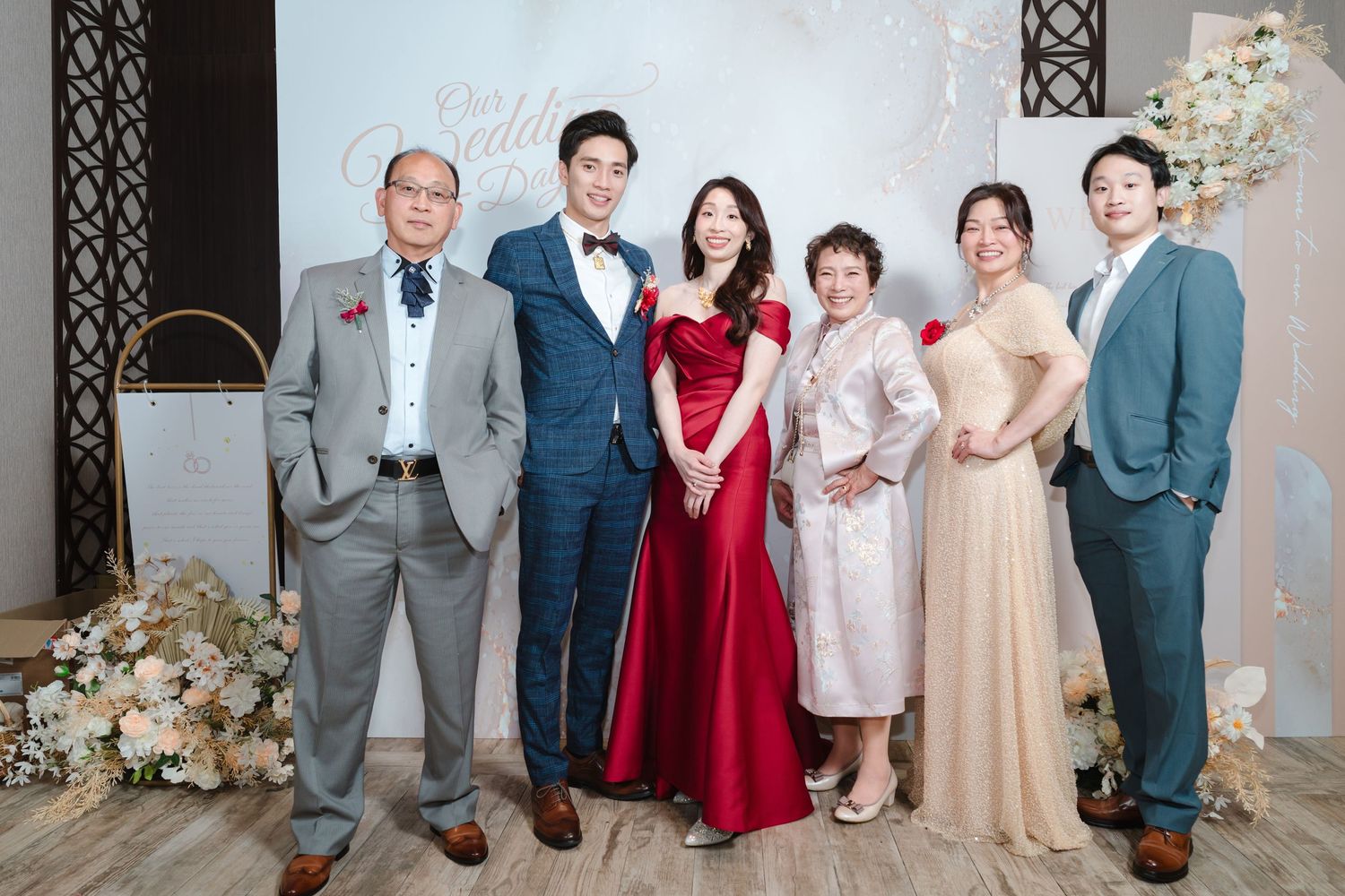 A formal group photo at an elegant event with floral decorations against a light colored backdrop.