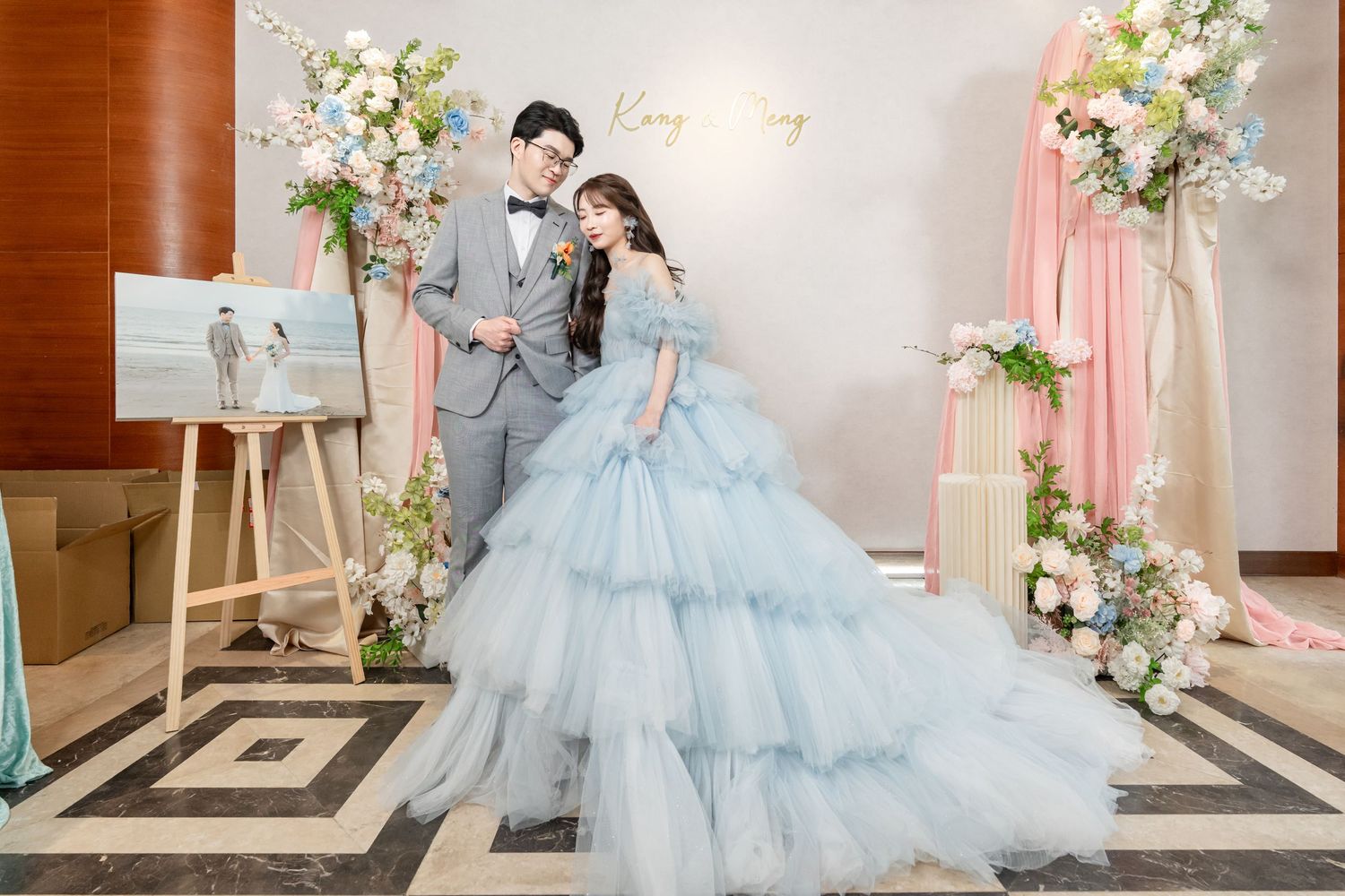 A romantic wedding photoshoot scene with soft blue tulle gown and floral decorations in an elegant indoor setting.