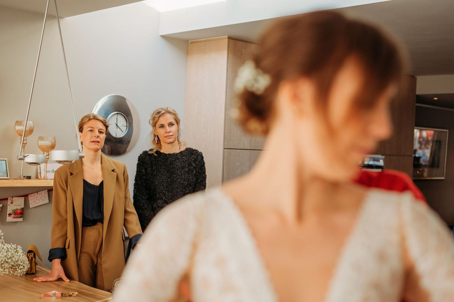 Drie vrouwen delen spontaan moment tijdens getting ready in warme binnenruimte, sfeervolle bruidsfotografie bij Boscafé Oisterwijk, Brabant.