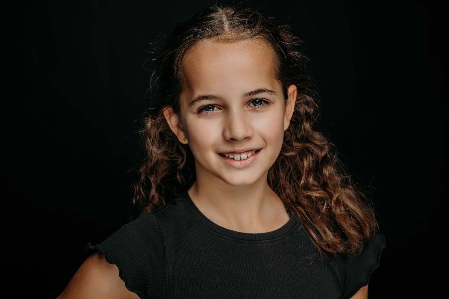 Portret van meisje met krullen in studio met donkere achtergrond, krachtige en pure fotografie