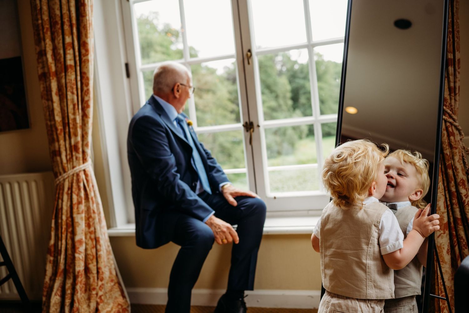 Interieur met grote ramen en bloemige gordijnen tijdens trouwvoorbereiding, trouwfotograaf Brabant.
