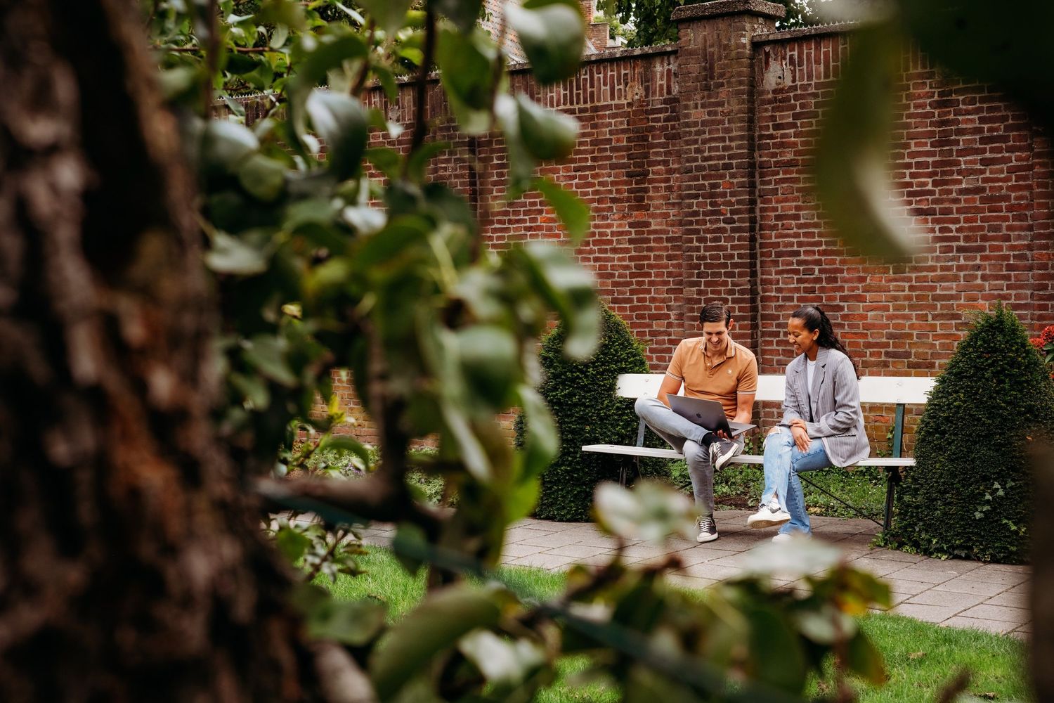 Studenten studeren en ontspannen op banken buiten historische universiteitsgebouwen, lifestyle fotografie Brabant