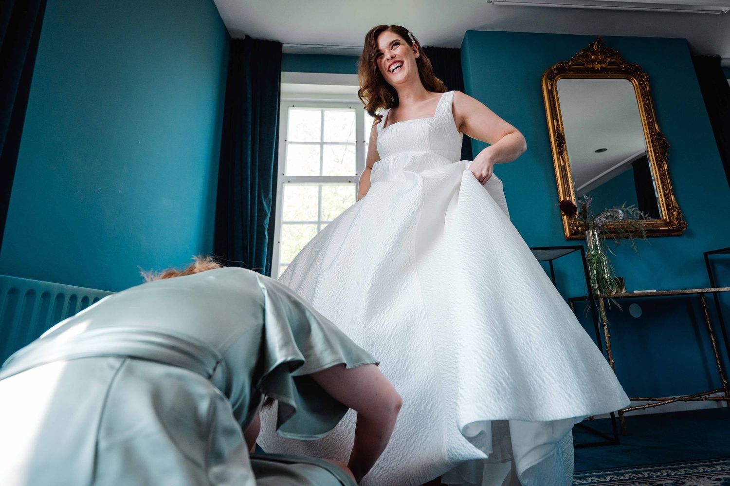 Elegante bruid voorbereidingen in een kamer met blauwe muren en natuurlijk licht, bruidsfotografie Brabant