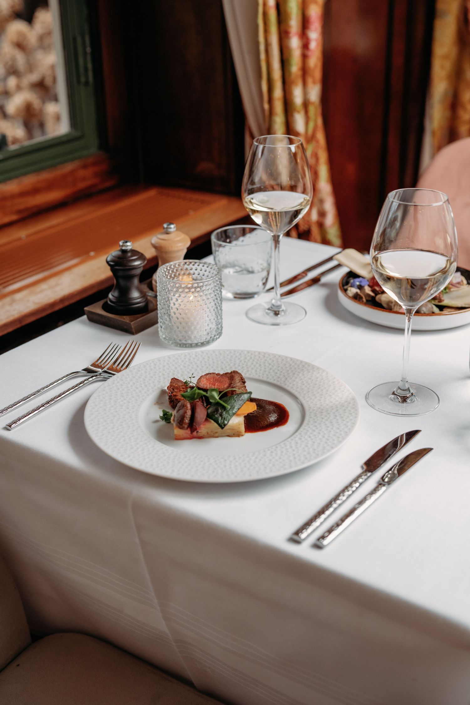 Fine dining tafelsetting met wit linnen en hoofdgerecht, foodfotografie Brabant