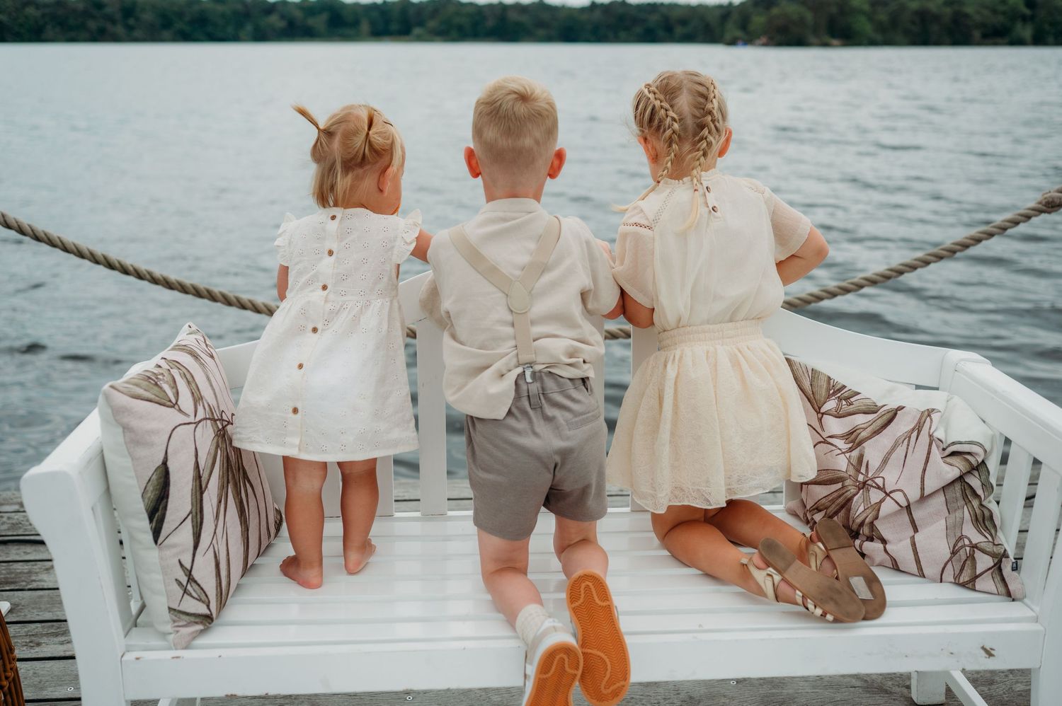 Drie kinderen in lichte kleding kijken uit over meer vanaf wit dek, gezinsfotografie Vught, Brabant.