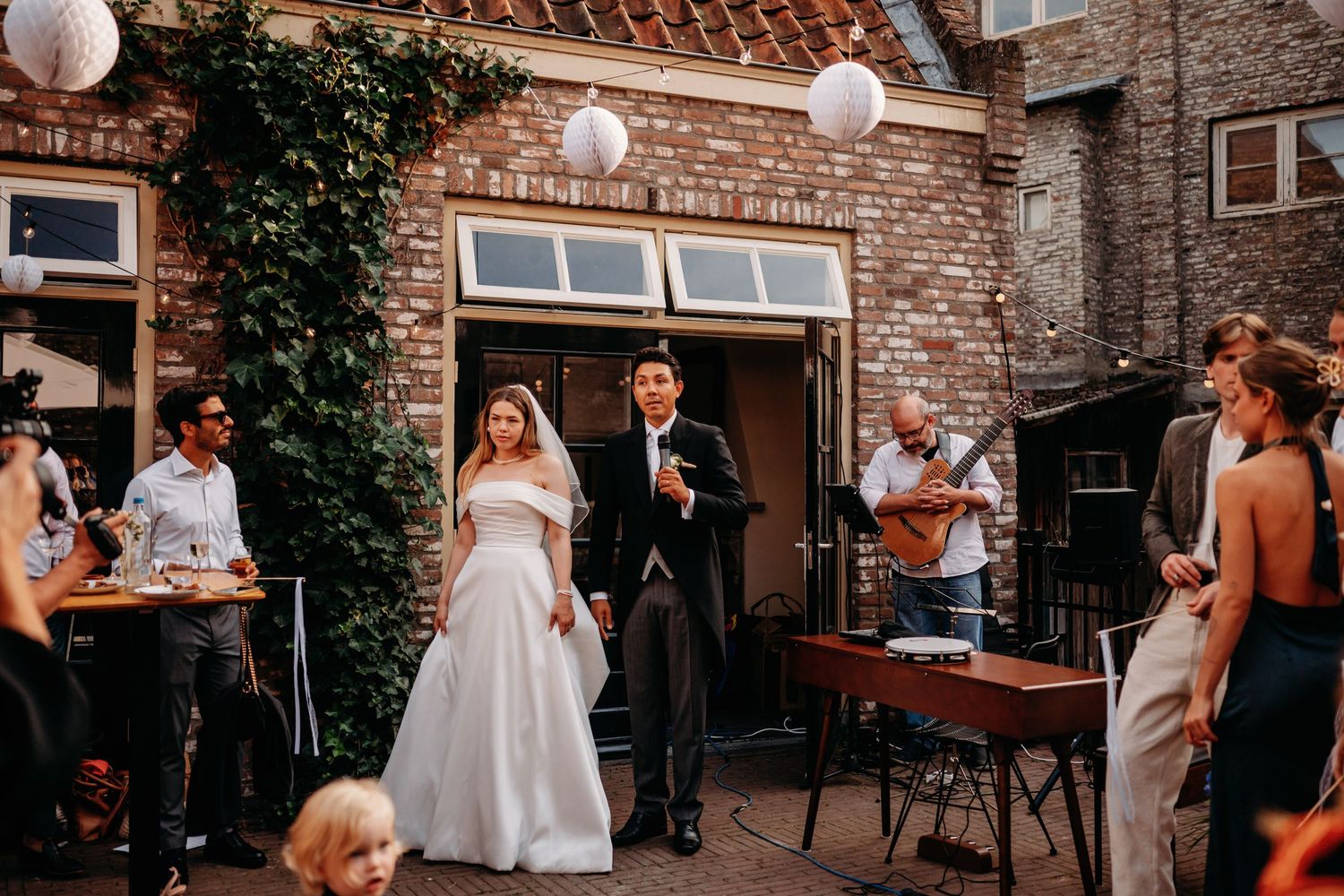 Buitenceremonie bij rustiek bakstenen pand met lichtslingers en groen decor, bruidsfotografie Noordbrabants Museum Den Bosch, Brabant.