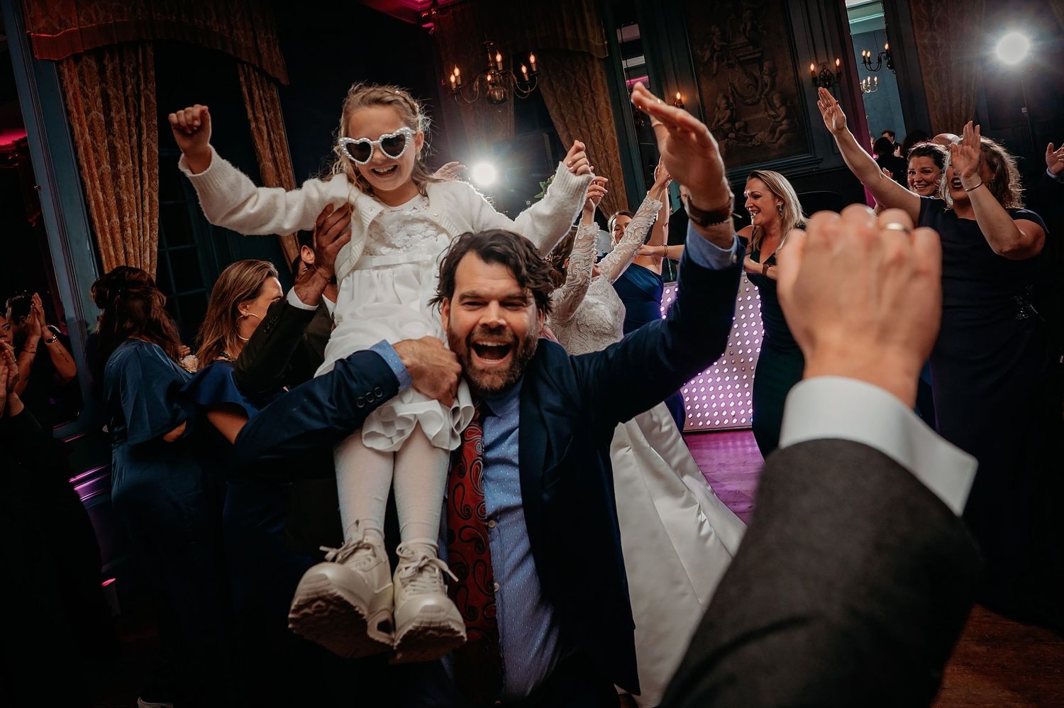 Dansfeest op de receptievloer met gasten op donkere dansvloer, trouwfotografie Brabant.