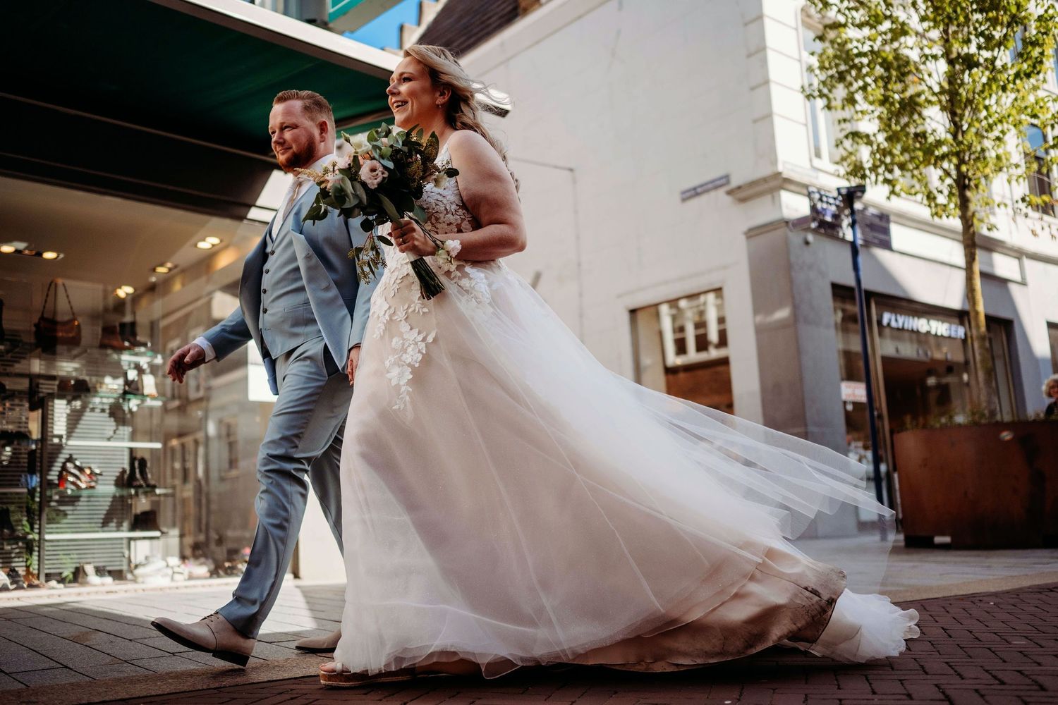 Bruidspaar voert romantische dip-dans uit op bakstenen straat, bruidsfotografie Den Bosch, Noord-Brabant.
