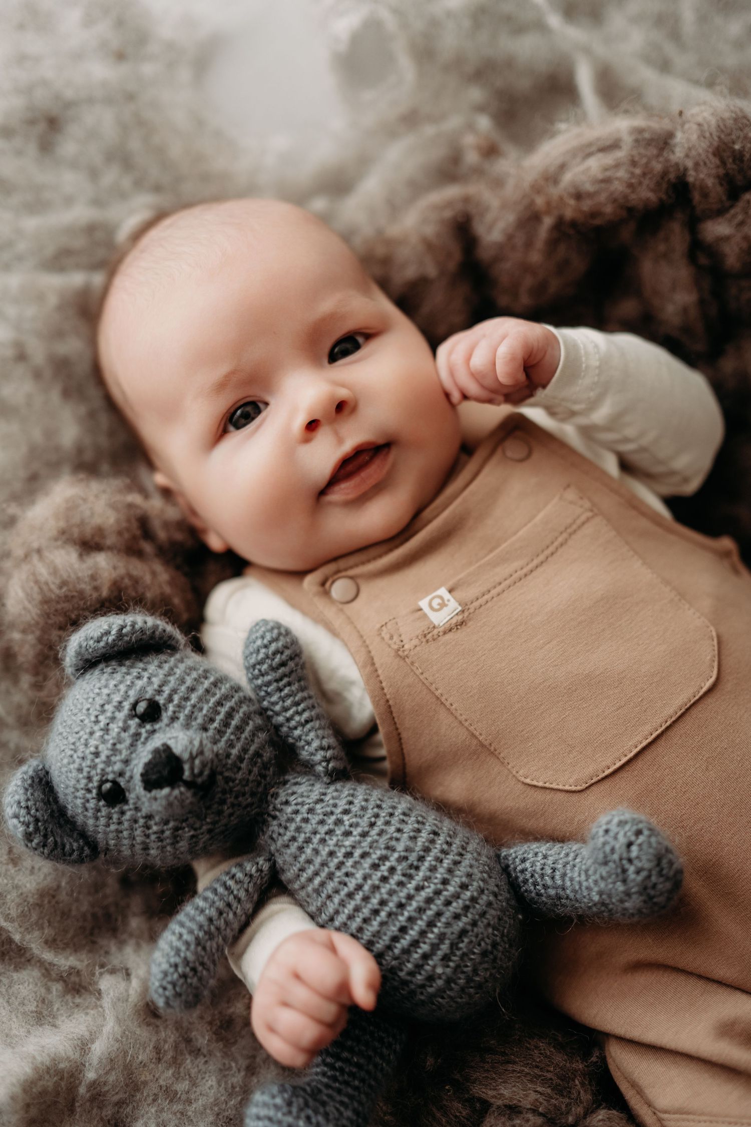 Pasgeboren baby tijdens newbornshoot in studio in Vught met teddybeer op zacht dekentje, warme natuurlijke fotografie door Ringelberg Fotogr