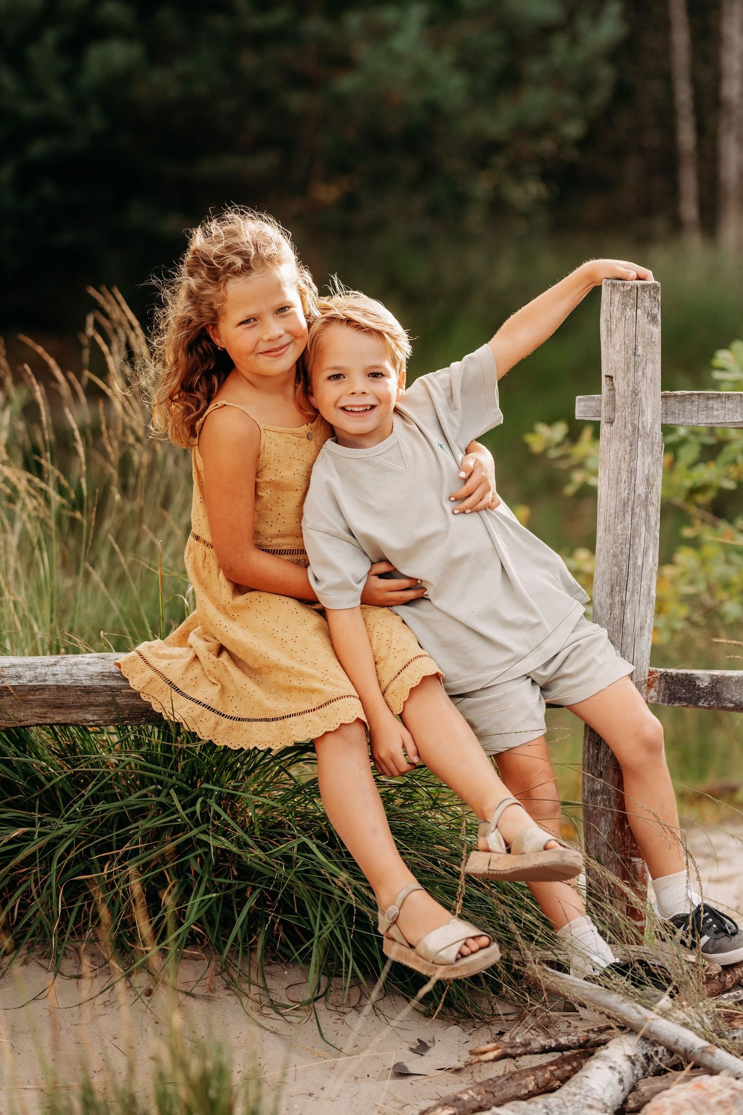 Kinderen zittend op houten hek tijdens een zomerse familieshoot in Brabant met natuurlijk licht