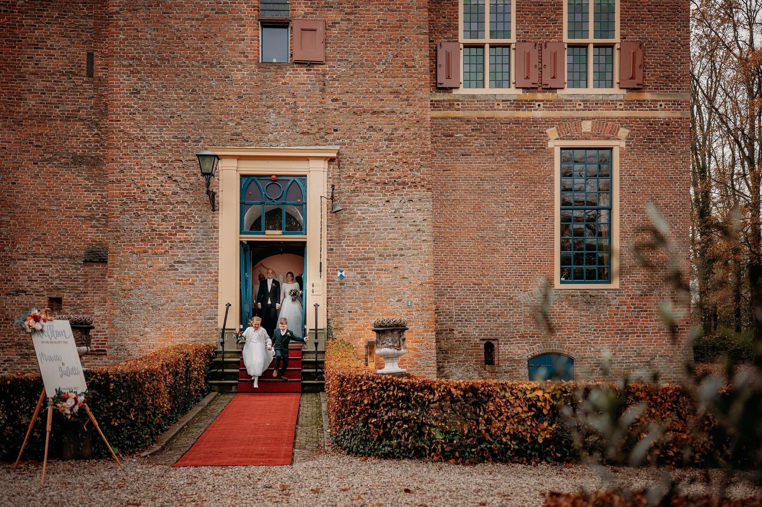 Entree van bruiloft bij historisch landhuis met rode loper, spontane bruidsfotografie bij Kasteel Wijenburg Echteld, Brabant.