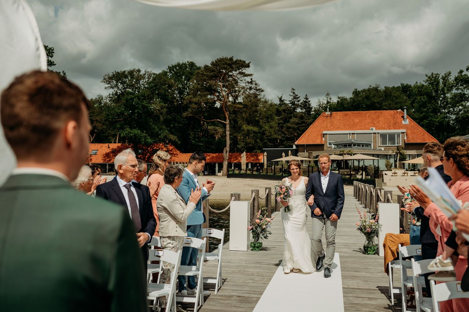 Buiten ceremonie bij water met witte stoelen en bloemen, bruidsfotografie IJM IJzereman Vught, Brabant.
