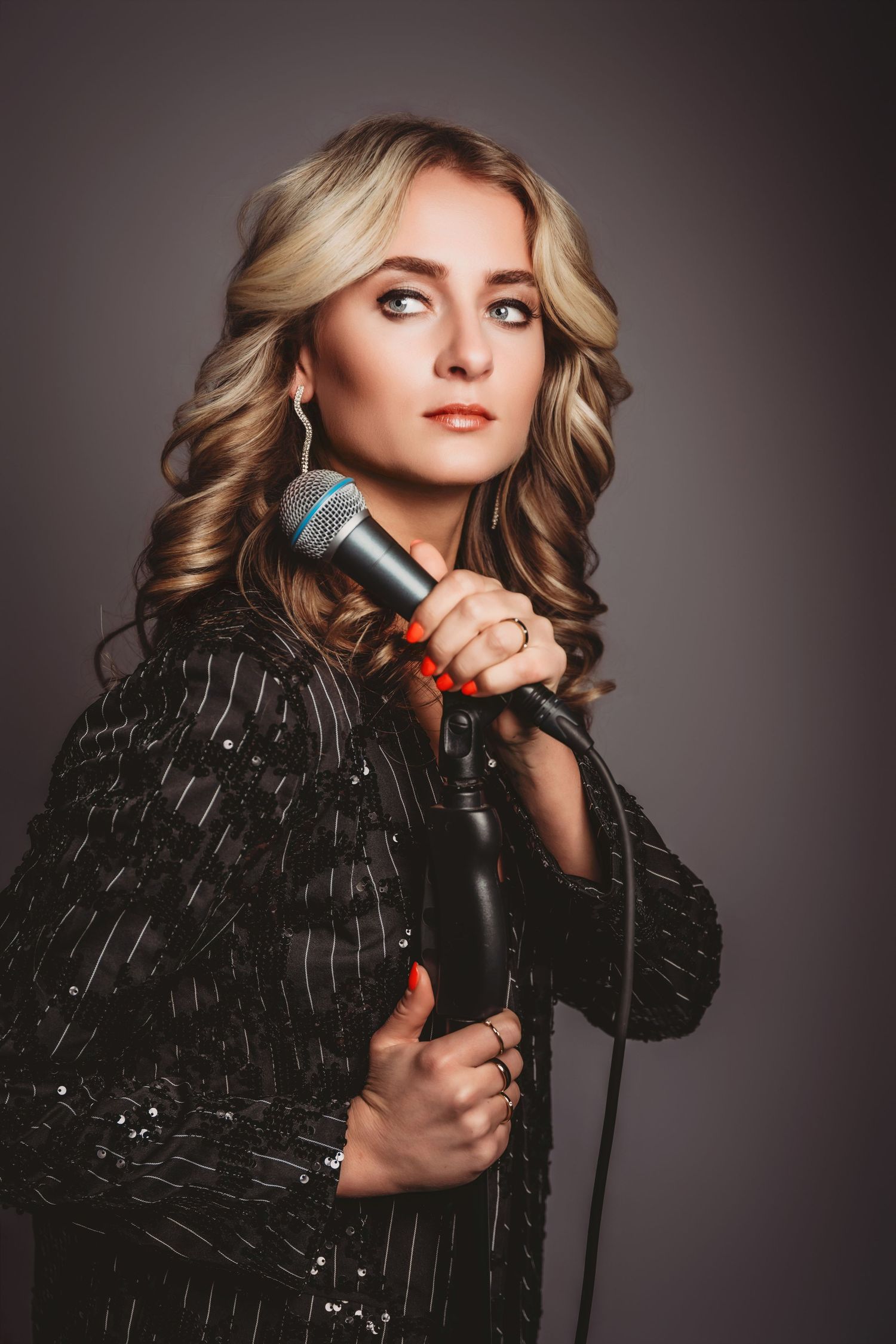 Dramatische portretserie van performer in zwart glinsterend outfit met microfoon, fashion/fotografie Brabant