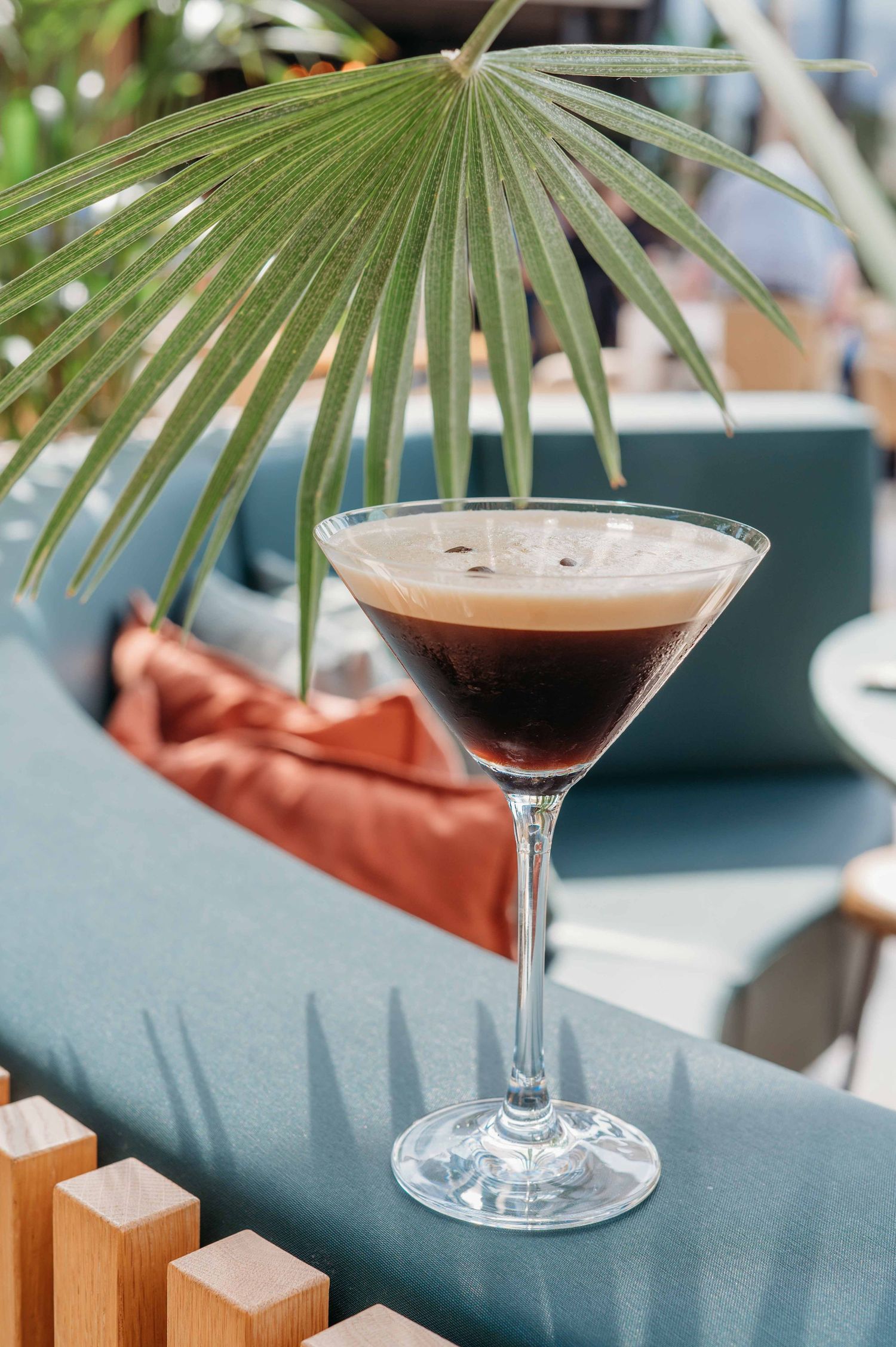 Tropische cocktail in martiniglas met palmbladeren tegen teal achtergrond, foodfotografie Brabant
