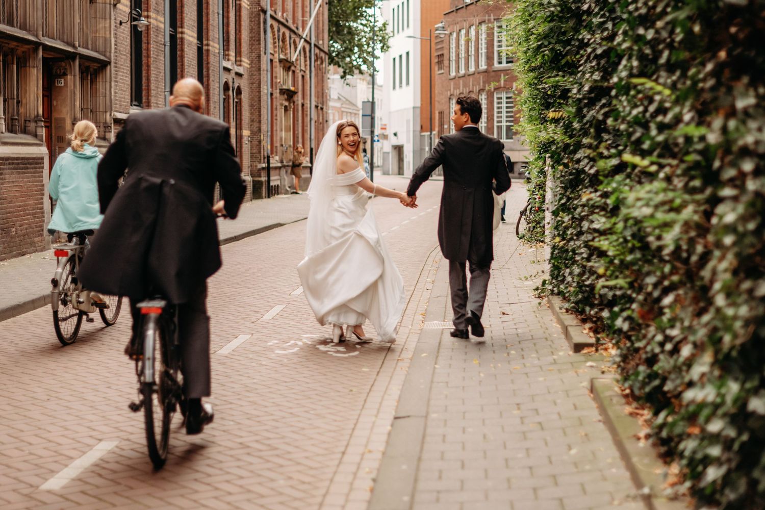 Mensen wandelen en fietsen door smalle bakstenen straat tussen historische gebouwen, bruidsfotografie Noordbrabants Museum Den Bosch, Braban
