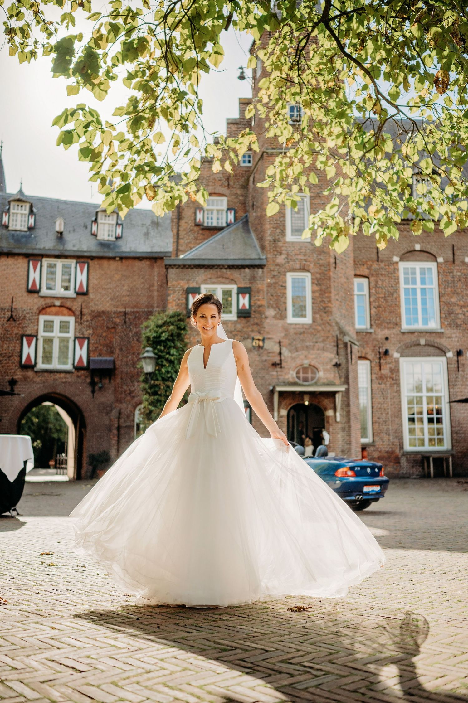 Trouwjurk draait elegant tegen bakstenen gebouw, bruidsfotografie Kasteel Maurick Vught, Brabant.