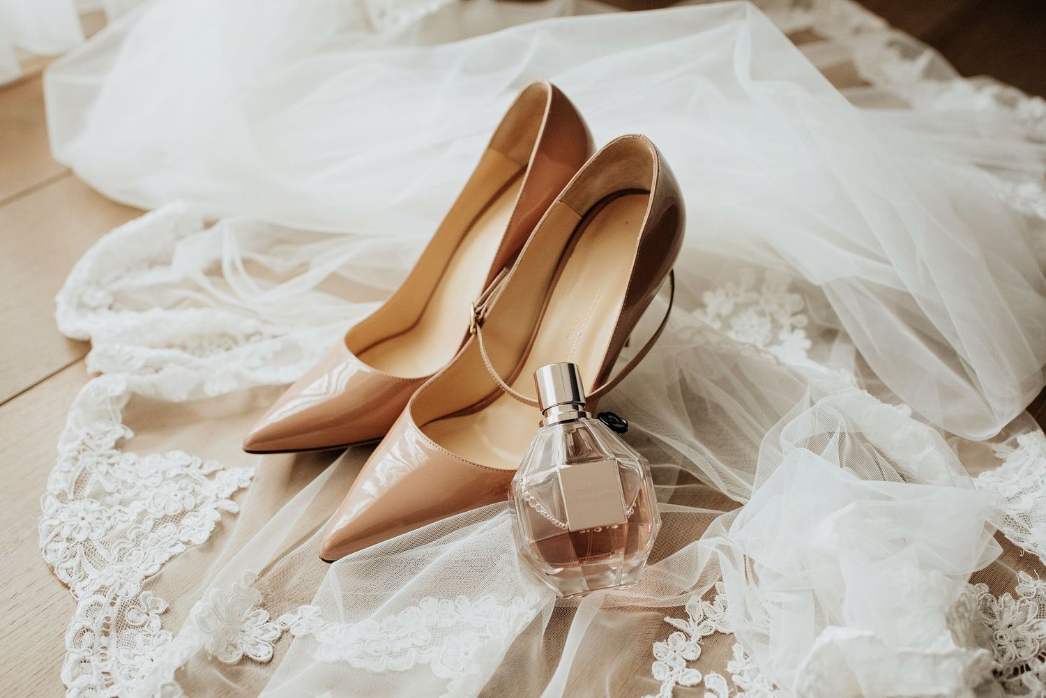 Elegante nude trouwschoenen geplaatst op een delicate witte sluier.