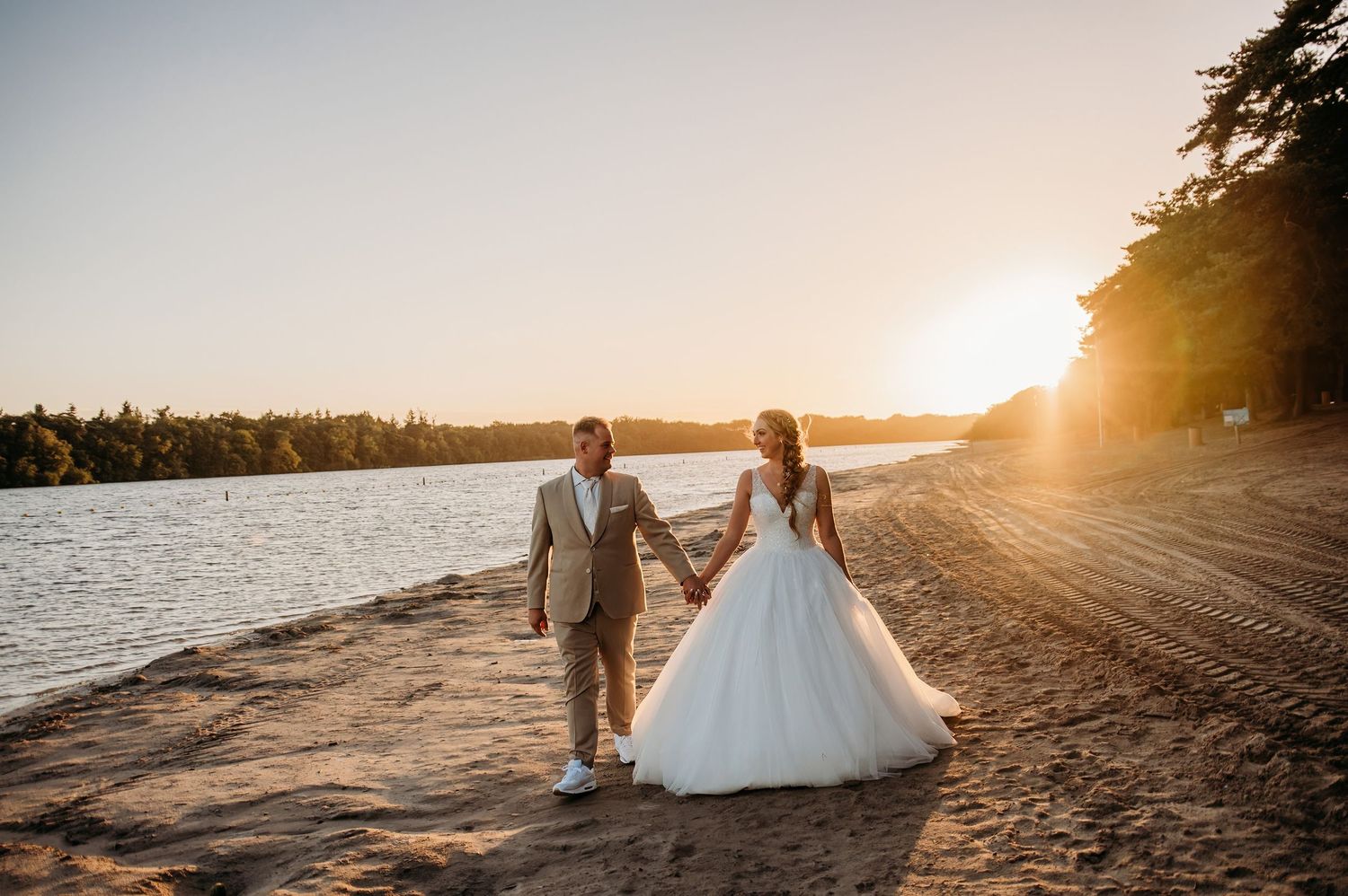 Romantische bruiloft op strand bij zonsondergang met water op achtergrond, bruidsfotografie IJM IJzereman Vught, Brabant.