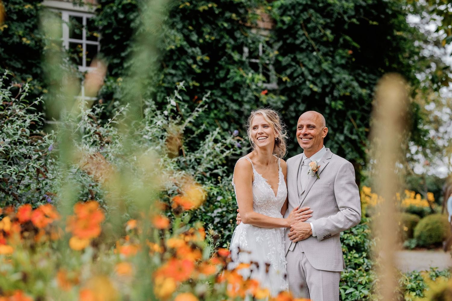 Romantische fotoshoot in tuin met oranje bloemen en groen, zwangerschaps- of koppelfotografie Vught, Brabant.