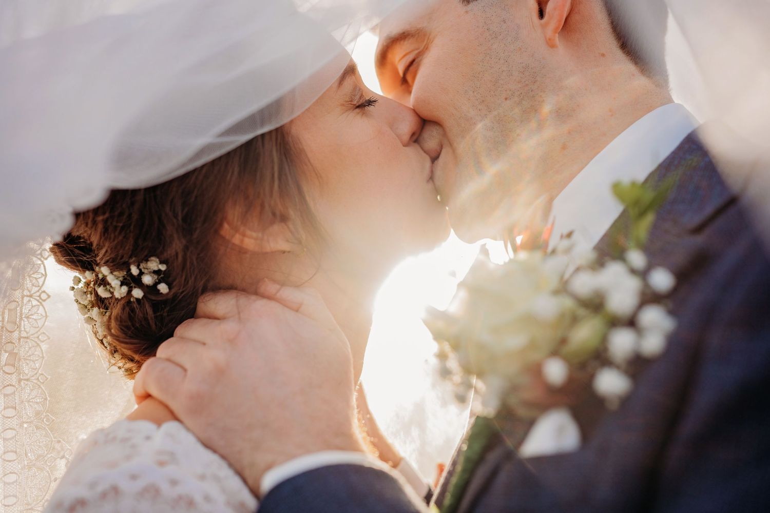 Intiem moment van bruidspaar in gouden zonlicht met bloemen, romantische bruidsfotografie bij Boscafé Oisterwijk, Brabant.