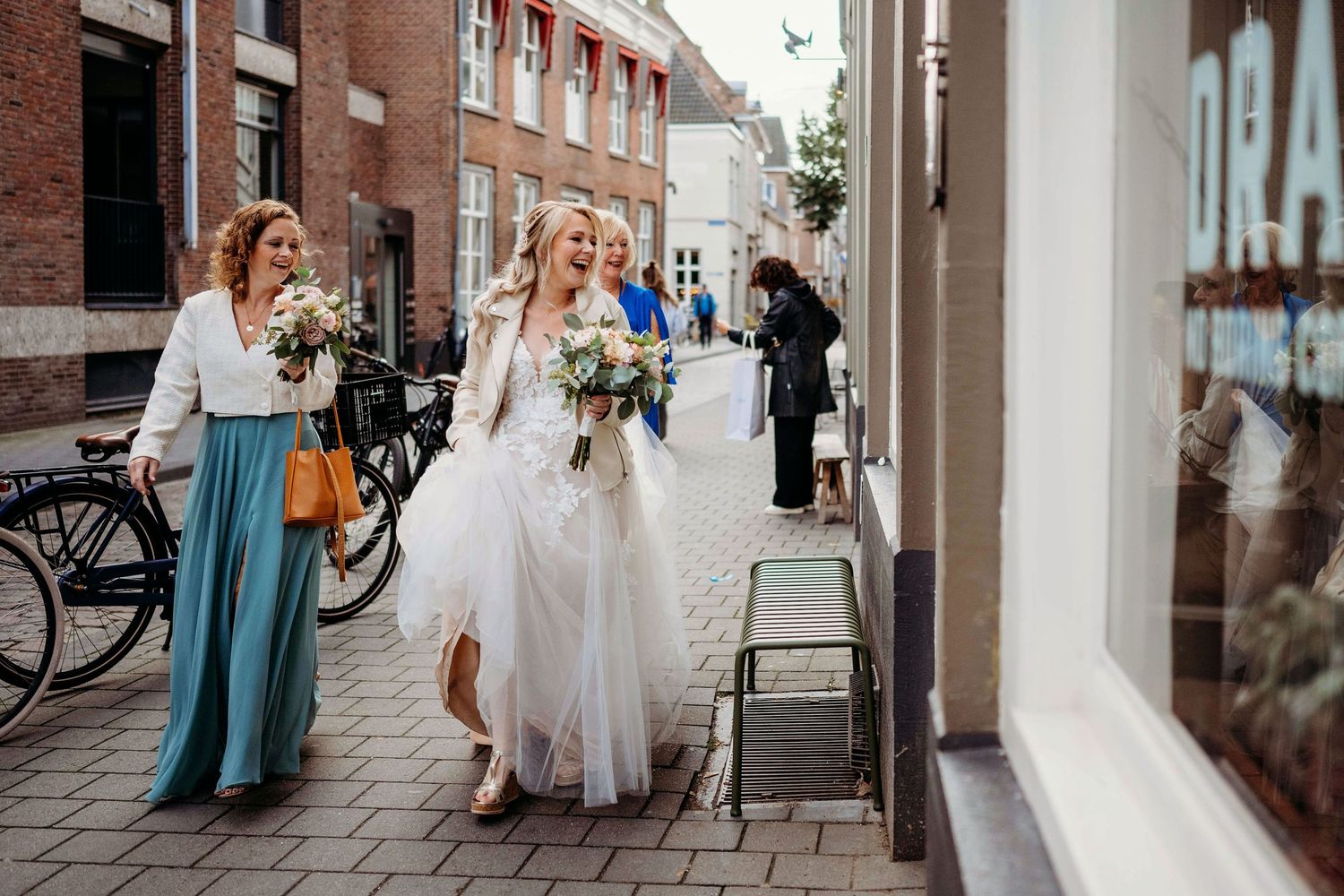 Bruiloftsgasten lopen door sfeervolle straat met historische gevels, spontane bruidsfotografie in Den Bosch en omgeving Brabant.