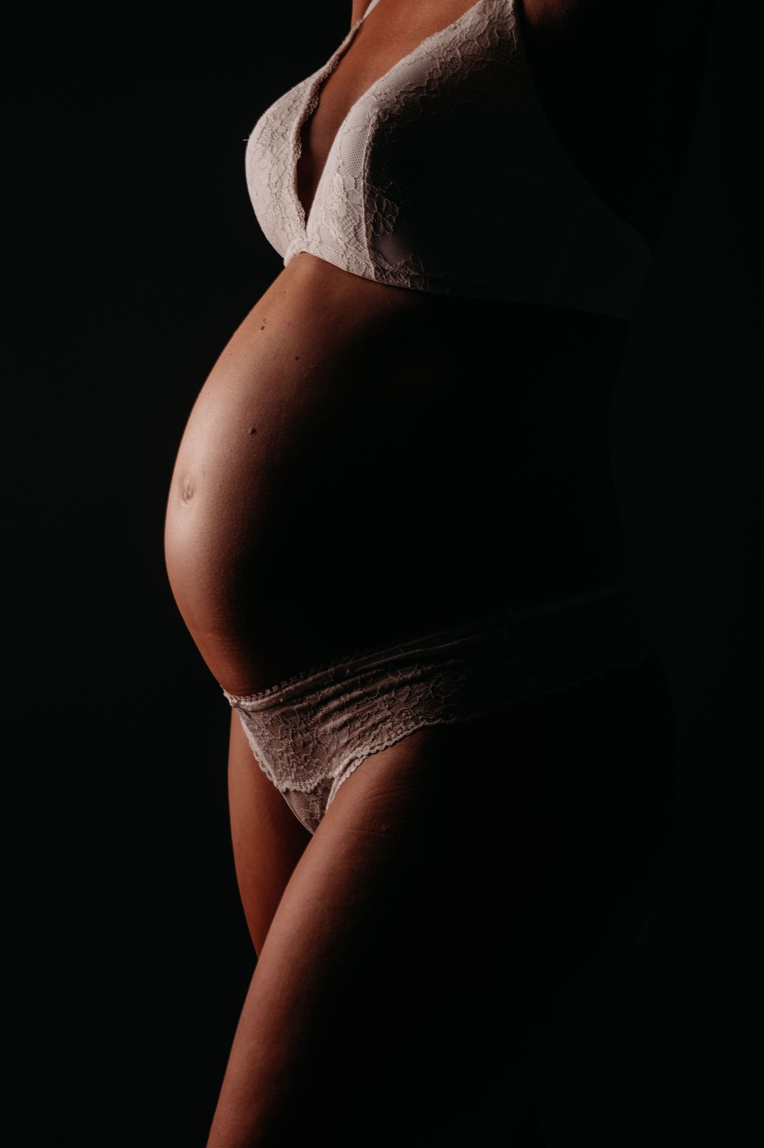 Artistic silhouette series capturing the curves of pregnancy against a dark background.