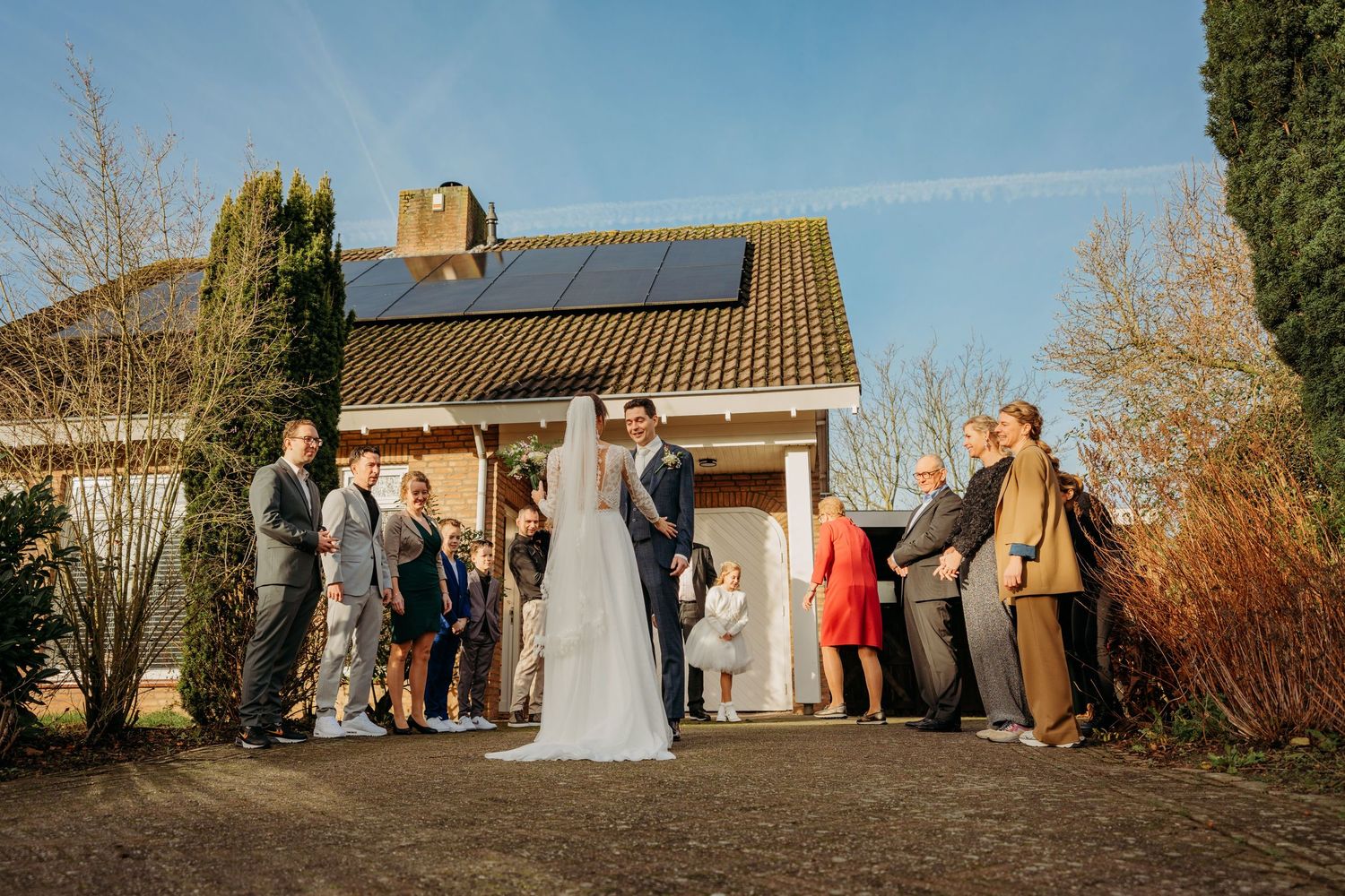 Vrolijke buitenviering met gasten in formele kleding op zonnige middag, bruidsfotografie bij Boscafé Oisterwijk, Brabant.