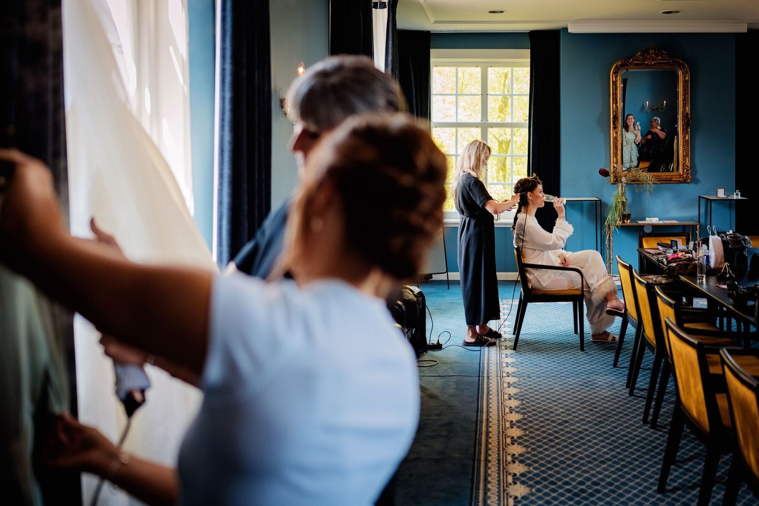 Interieur van locatie met blauwe muren en natuurlijk licht door ramen tijdens bruidvoorbereidingen, bruidsfotografie Brabant