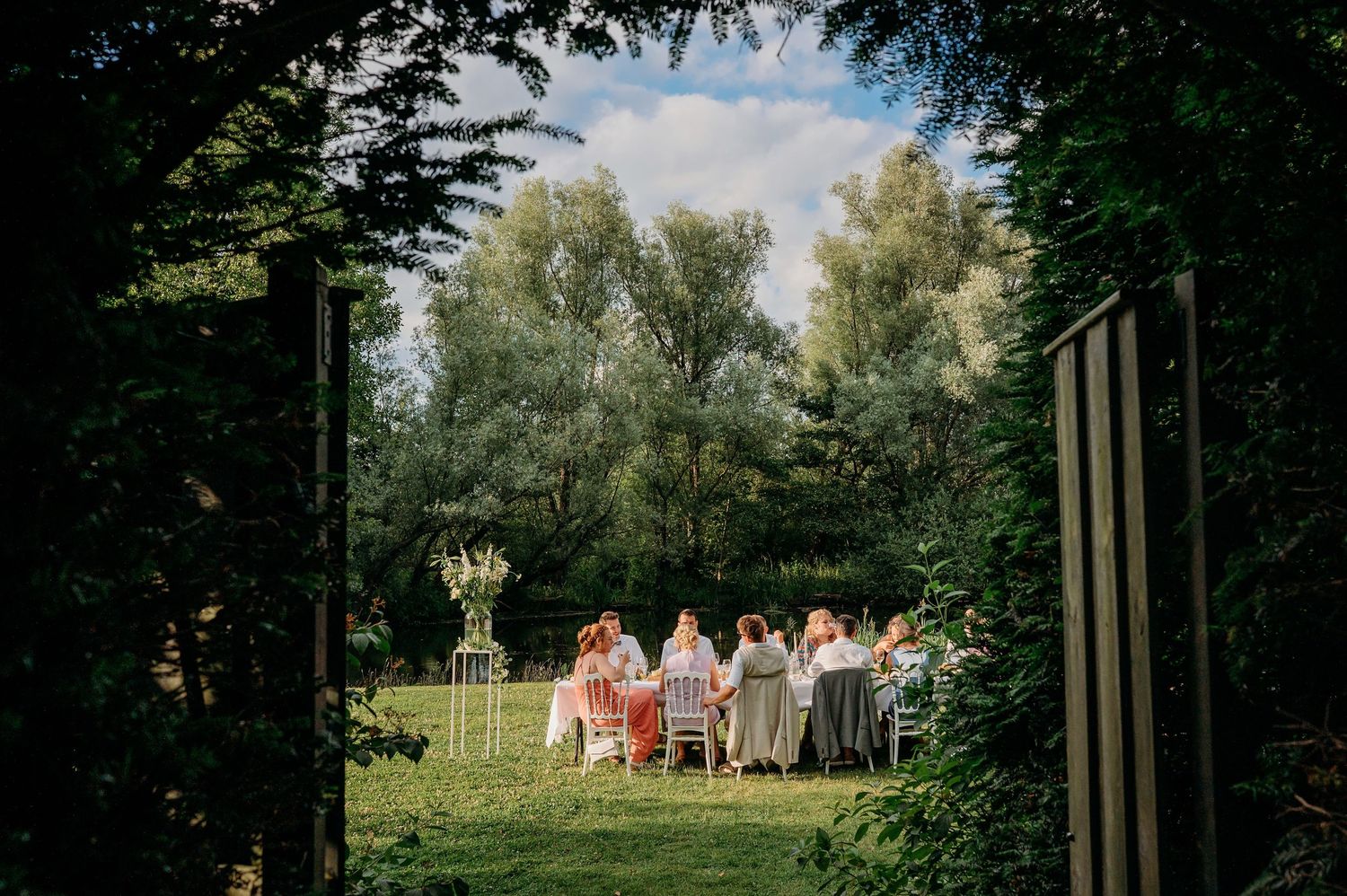Bruiloftsgasten op het gras met zichtbaar vloeiende witte jurk, trouwfotografie Brabant.