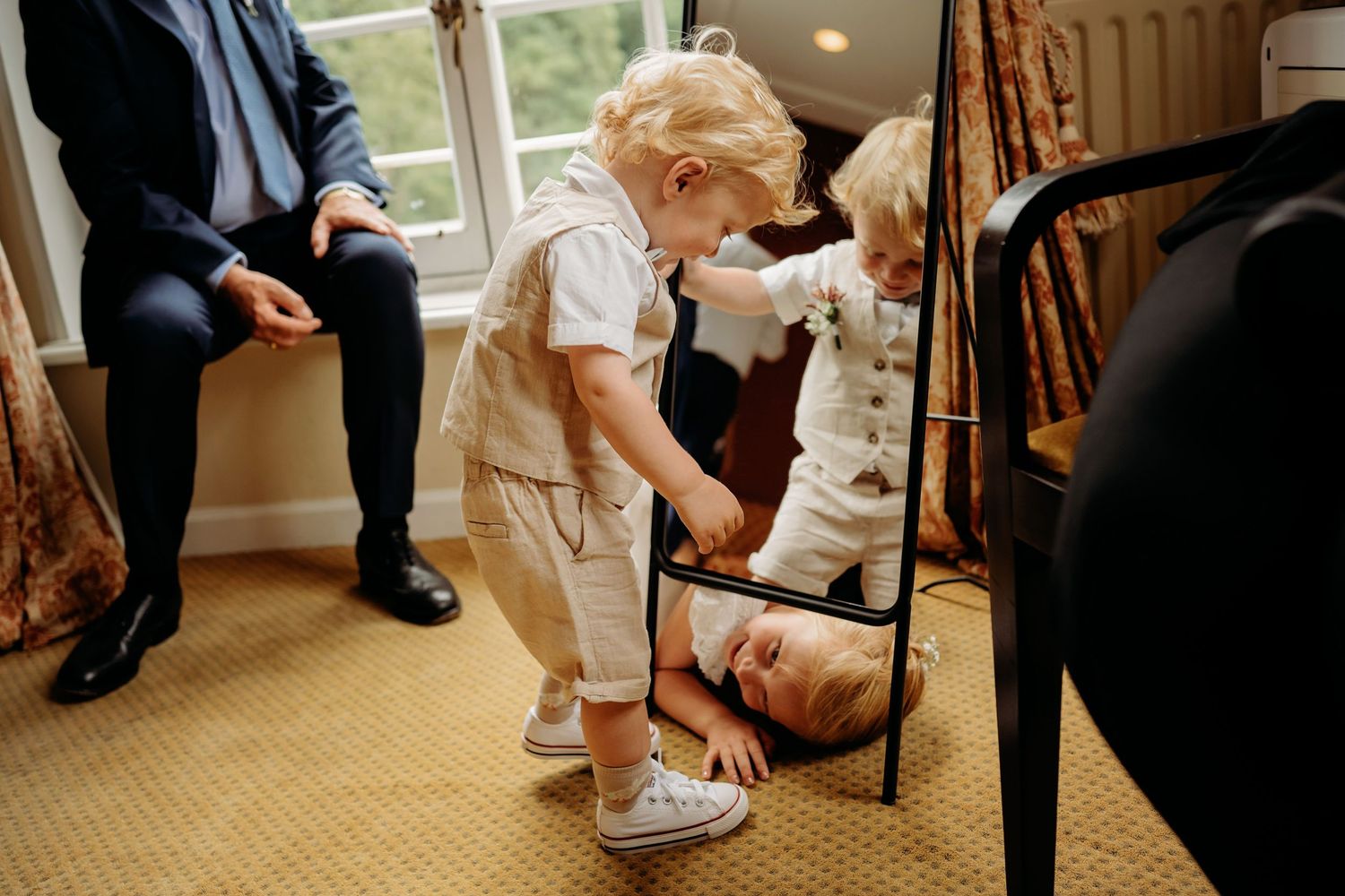 Kleine kinderen in formele kleding spelen bij voeten van volwassenen tijdens bruiloft, bruidsfotografie Brabant
