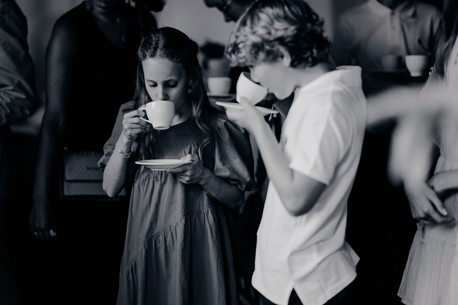 Two children drinking from white teacups at a wedding reception in a black and white photo.