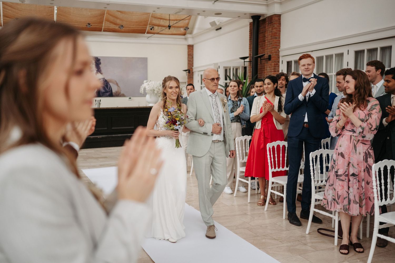 De bruid loopt samen met haar vader naar de ceremonie tijdens een bruiloft bij Kasteel Maurick.