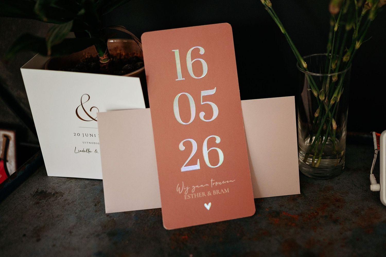 Elegant wedding save the date card showing 16 05 26 in white text on a terracotta pink background.