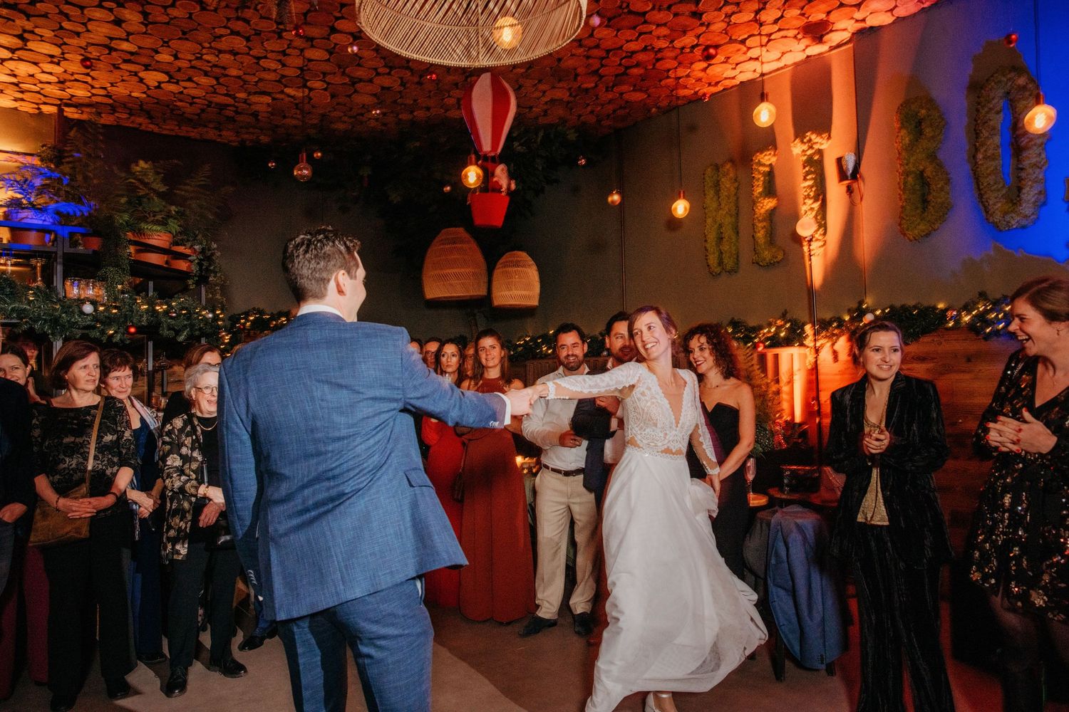 Bruiloftsfeest op dansvloer met warm oranje licht, spontane bruidsfotografie bij Boscafé Oisterwijk, regio Brabant.
