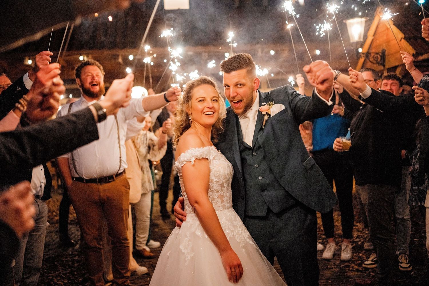 Sparklers illuminate nighttime wedding celebration creating magical light trails.