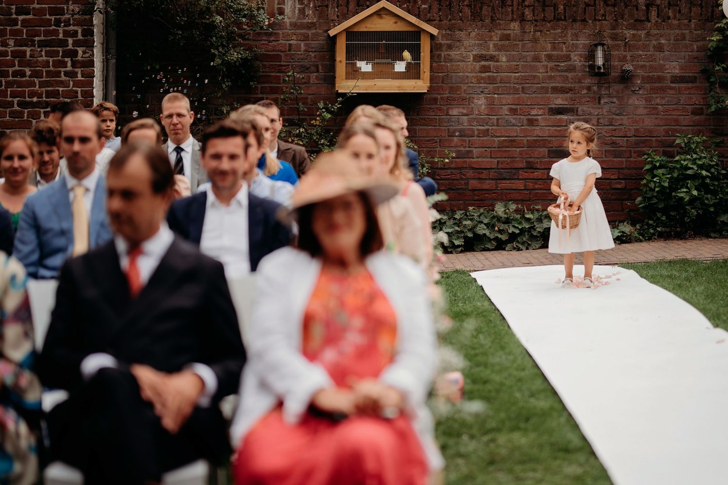 Buitenceremonie met bakstenen muur en witte loper, bruiloftsfotograaf Brabant.