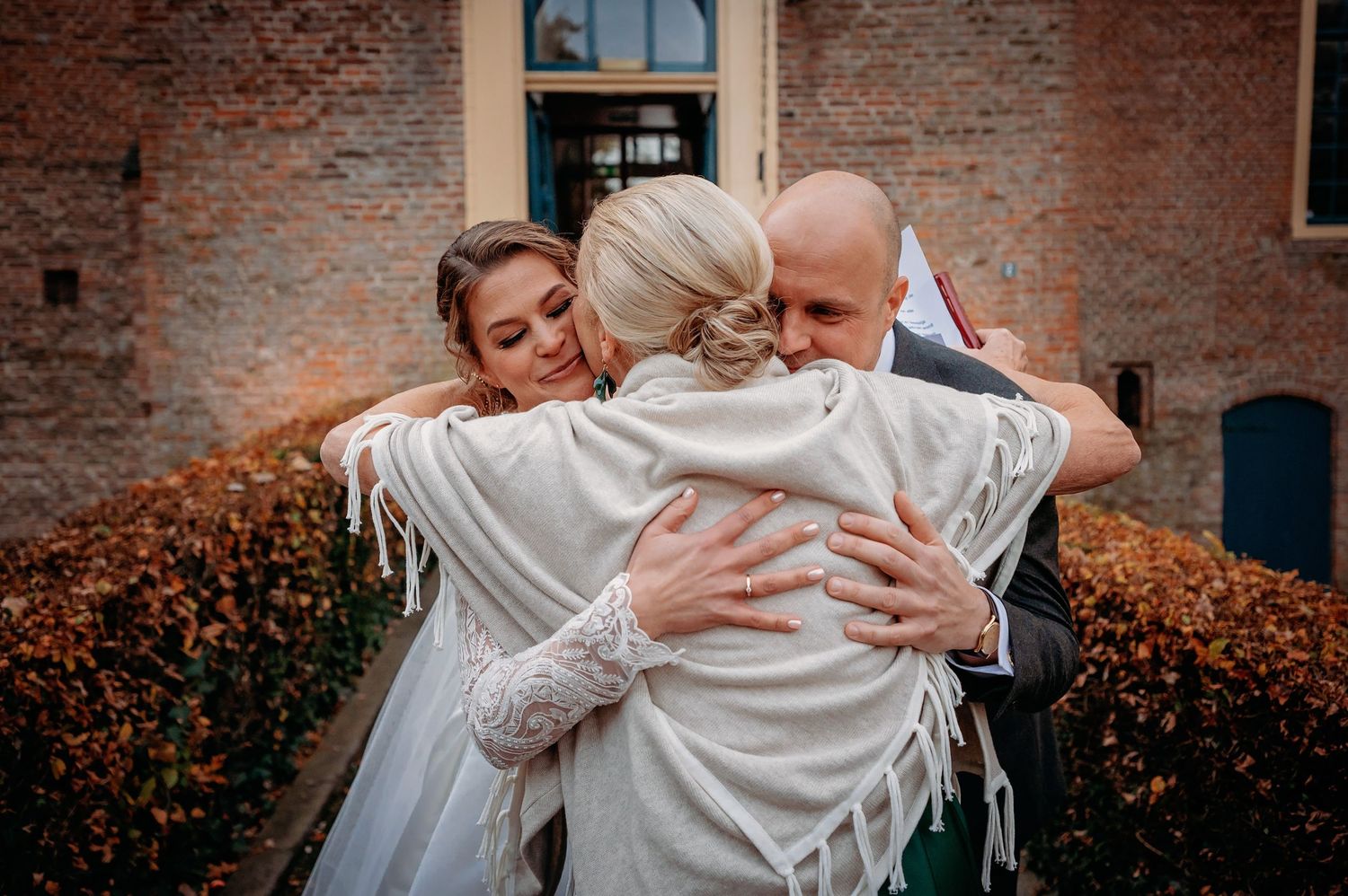 Emotioneel trouwmoment bij bakstenen muur met omhelzing, romantische bruidsfotografie bij Kasteel Wijenburg Echteld, Brabant.