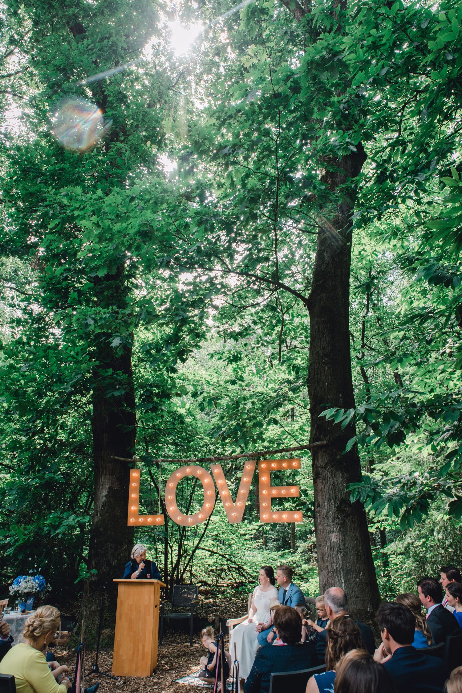 Bruidspaar danst bij verlichte LOVE letters in bos tijdens avond van hun bruiloft in Brabant