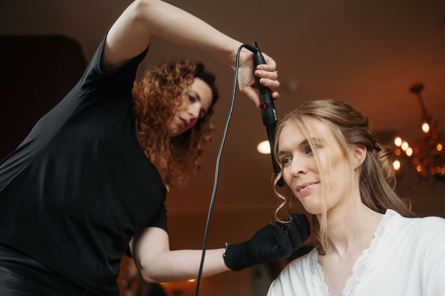 De visagiste werkt aan de finishing touch van de bruidsmake up tijdens de voorbereidingen.