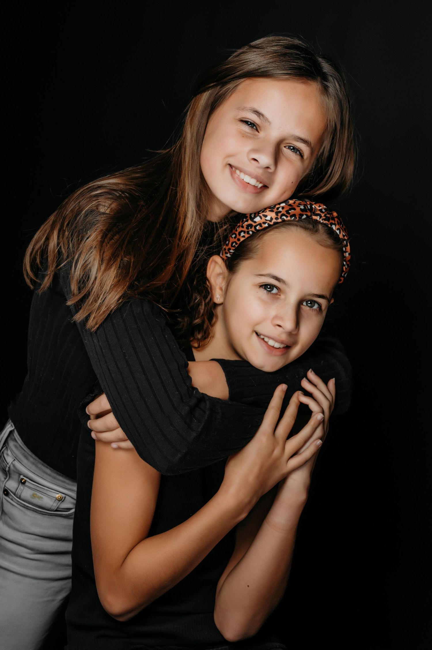Studioportrait van twee personen in zwarte tops met speelse poses tegen donkere achtergrond, portretfotografie Brabant