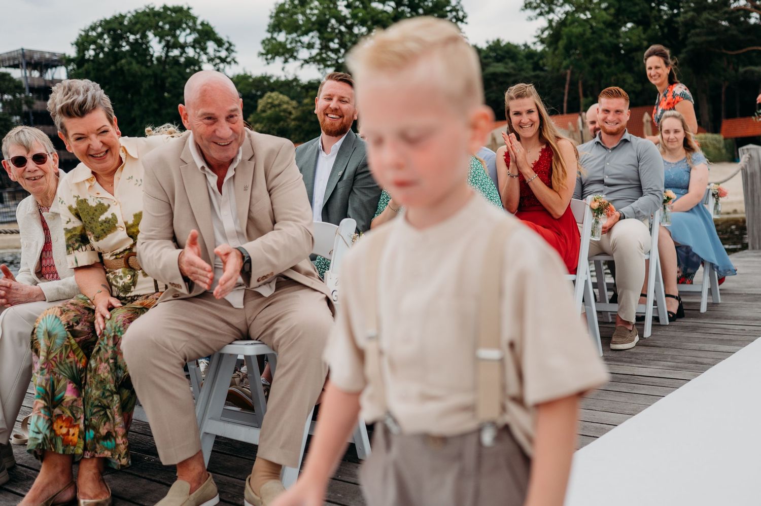 Gasten zittend buiten in lichte zomerkleding, bruidsfotografie Brabant.