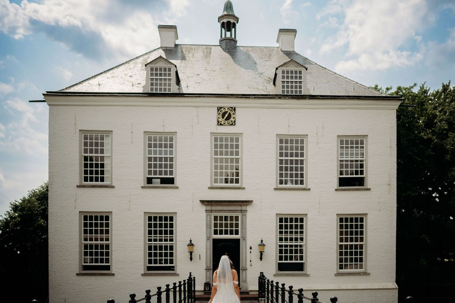 Panoramic view of a white colonial style building with symmetrical windows under blue sky.