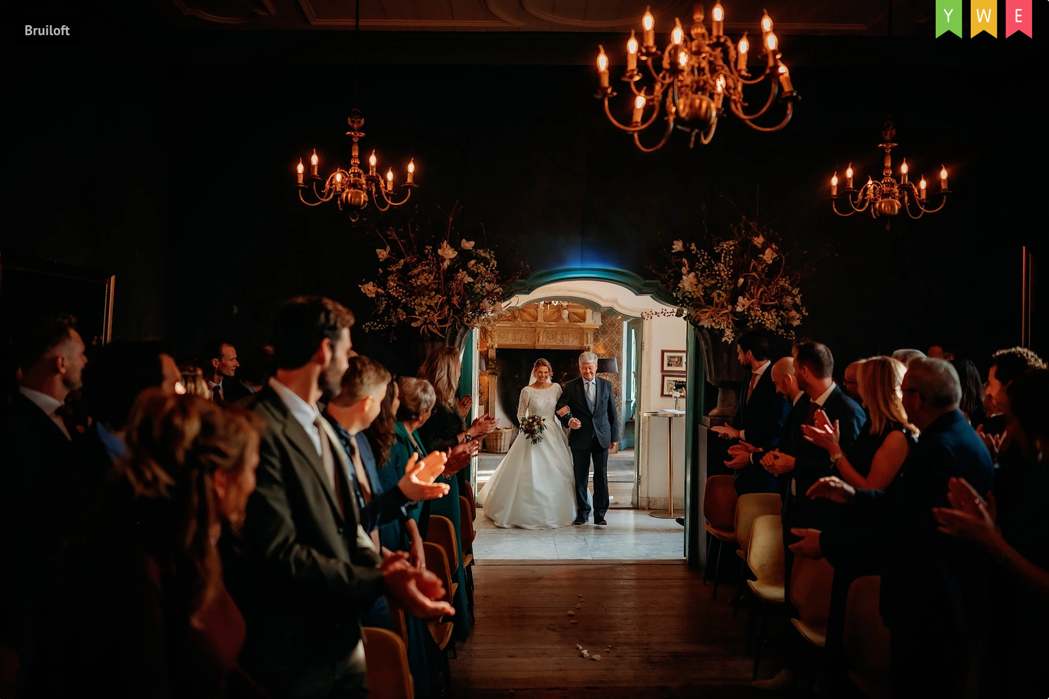 Donkere receptiehal met kroonluchters en silhouetten van bruiloftsgasten, bruidsfotografie Brabant