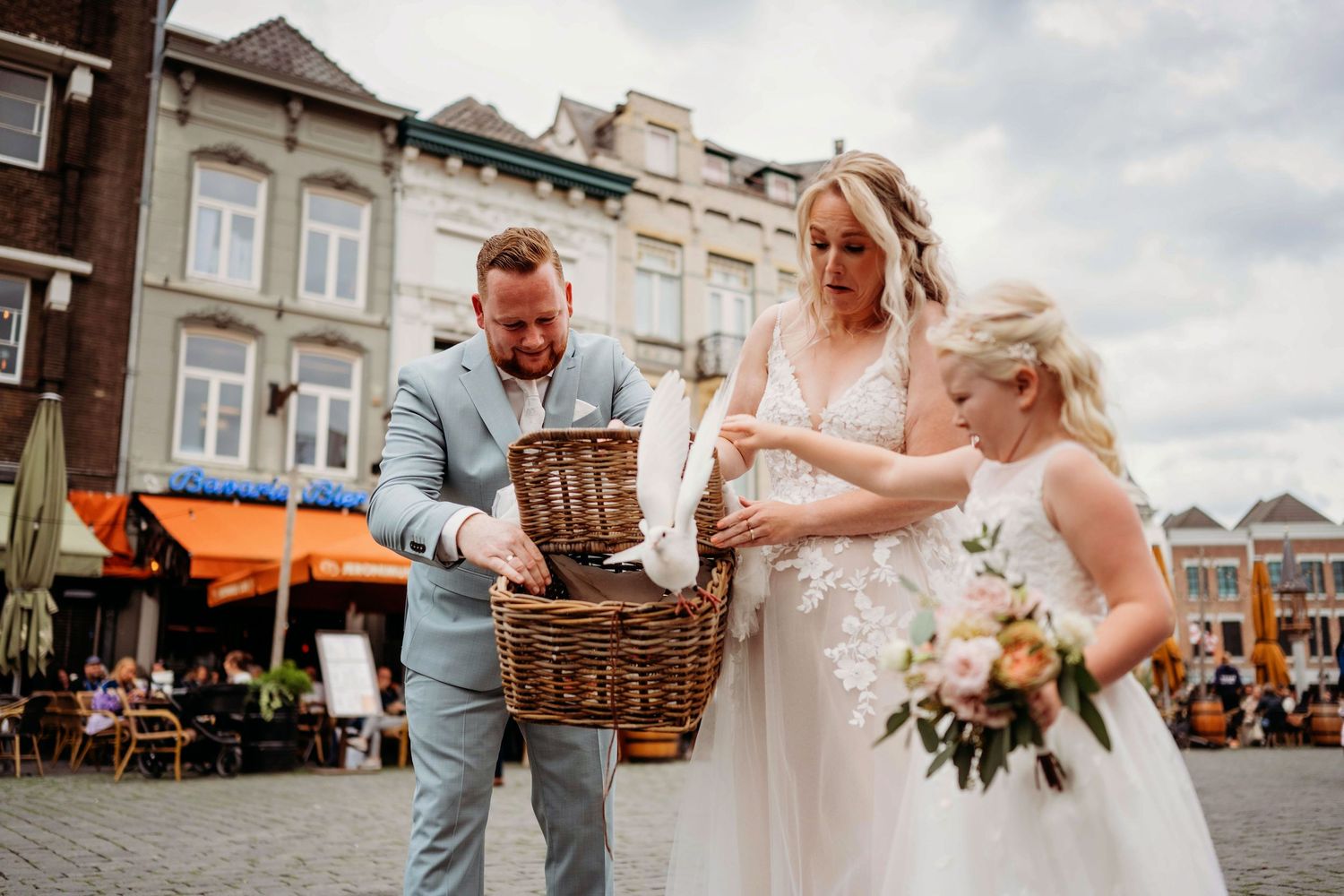 Bruiloftsgasten bekijken rieten manden op kasseien, spontane bruidsfotografie in Den Bosch en omgeving Brabant.
